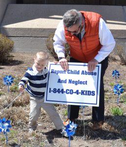 Commissioner Mark Waller and a young helper planted a sign to remind people to report child abuse and neglect on April 18, 2019, for Child Abuse Prevention Month.